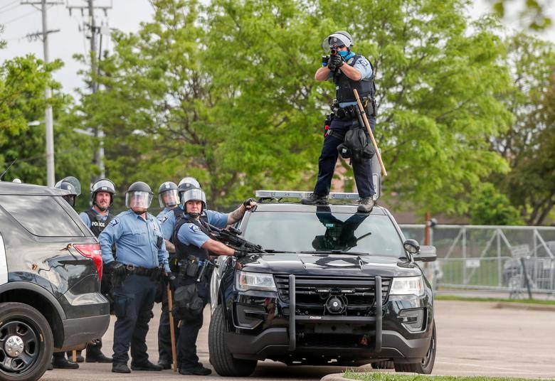 A police officer aims a gun before firing at protestors gathered near the Minneapolis Police third precinct after a white police officer was caught on a bystander's video pressing his knee into the neck of African-American man George Floyd, who later died at a hospital, in Minneapolis, Minnesota. REUTERS/Eric Miller  